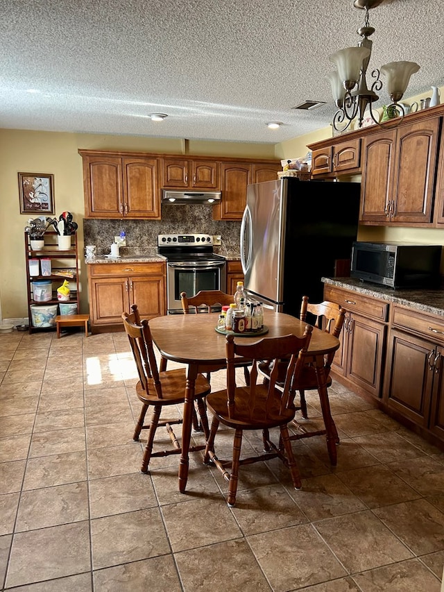 kitchen featuring decorative backsplash, tile patterned flooring, a textured ceiling, and appliances with stainless steel finishes