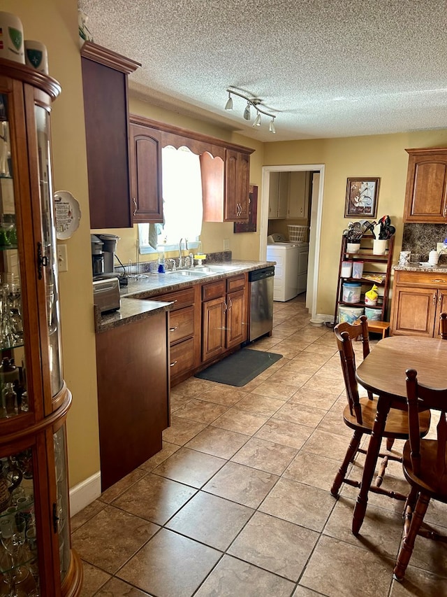 kitchen featuring stainless steel dishwasher, a textured ceiling, sink, independent washer and dryer, and light tile patterned flooring