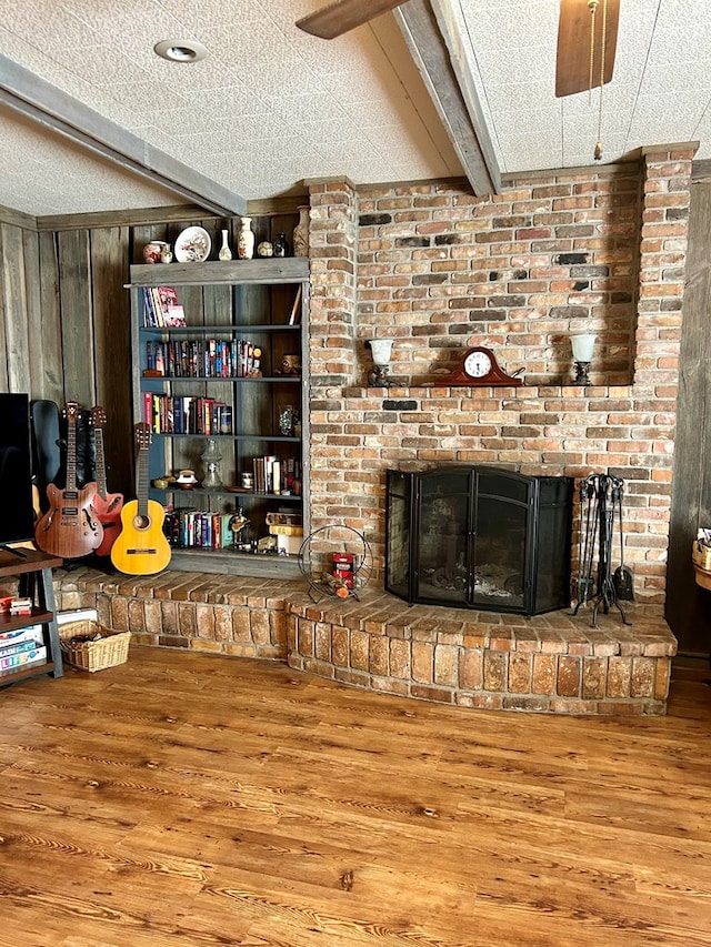 interior space featuring hardwood / wood-style flooring, a fireplace, wood walls, and a textured ceiling