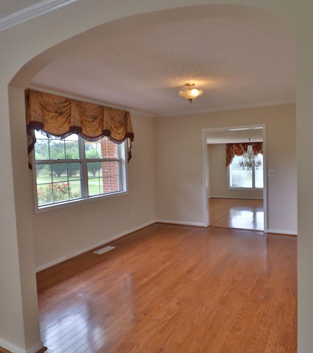 1222 E Main St, Ariton, AL 36311 - spare room with healthy amount of natural light, ornamental molding, wood finished floors, arched walkways, and a chandelier