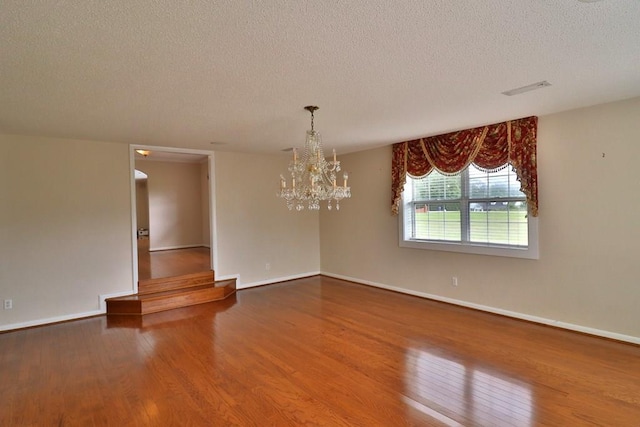 1222 E Main St, Ariton, AL 36311 - spare room with a textured ceiling, wood finished floors, and a chandelier