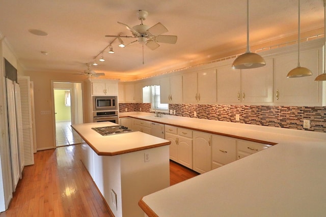 kitchen featuring white cabinetry, hanging light fixtures, a kitchen island, stainless steel appliances, and decorative backsplash