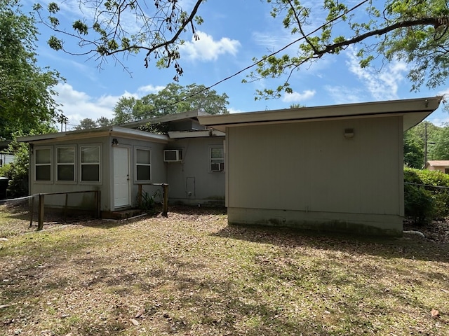 rear view of house with a wall mounted AC and fence