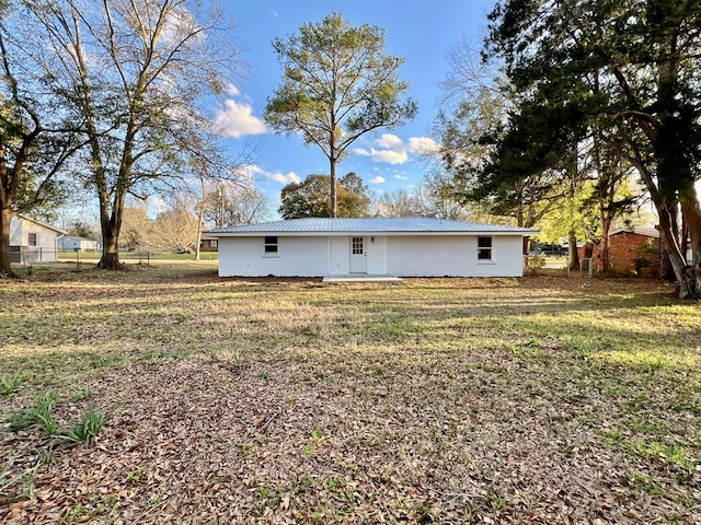 exterior space featuring fence, metal roof, and a lawn