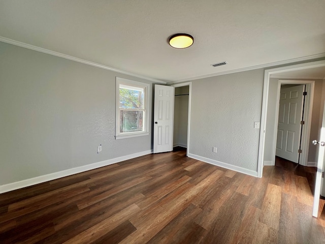 unfurnished bedroom with baseboards, dark wood-type flooring, crown molding, and a textured wall