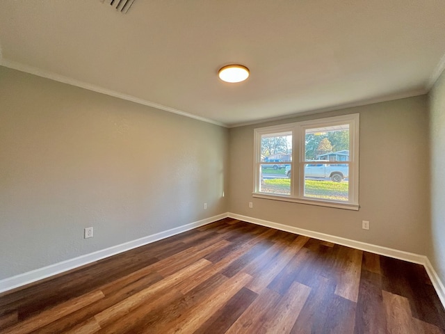 empty room featuring crown molding, dark wood-style flooring, visible vents, and baseboards