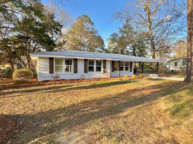 single story home featuring a carport, metal roof, driveway, and a front lawn