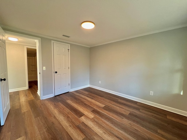 unfurnished bedroom featuring baseboards, visible vents, dark wood finished floors, and ornamental molding