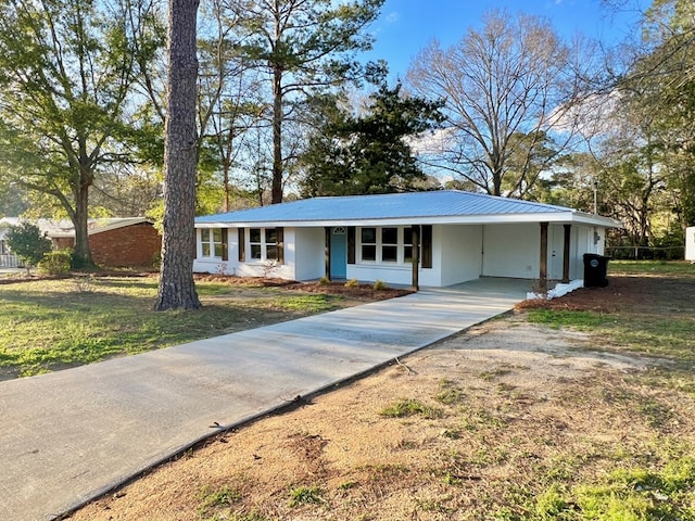 ranch-style house with a carport, a front yard, metal roof, and driveway