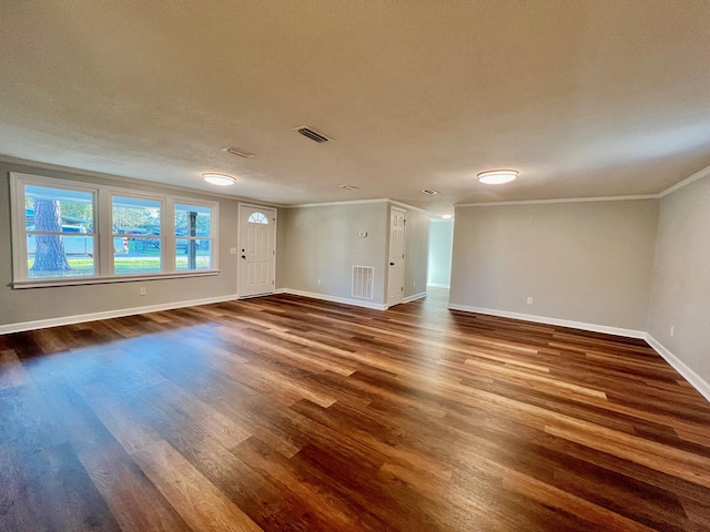 empty room featuring baseboards, dark wood-type flooring, visible vents, and crown molding