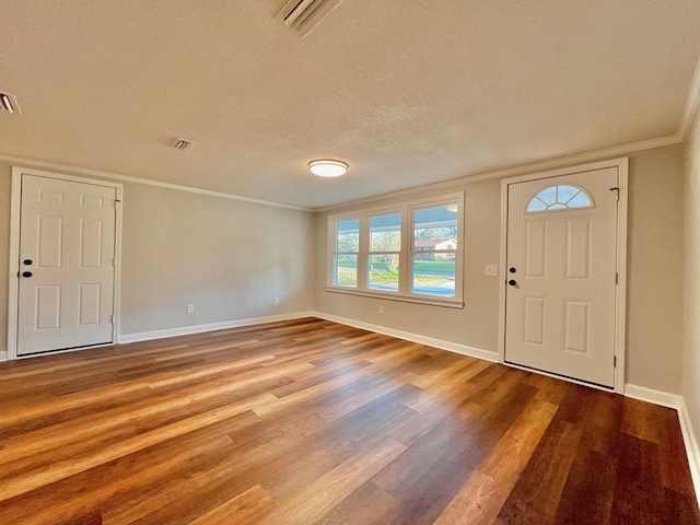 entryway featuring visible vents, ornamental molding, a textured ceiling, wood finished floors, and baseboards