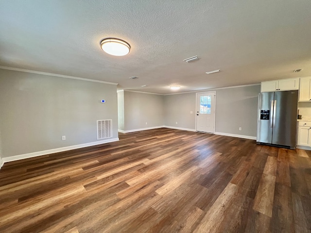 empty room featuring a textured ceiling, dark wood finished floors, visible vents, and baseboards