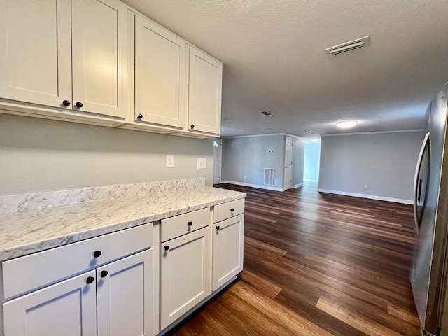 kitchen featuring dark wood-type flooring, visible vents, baseboards, white cabinetry, and freestanding refrigerator