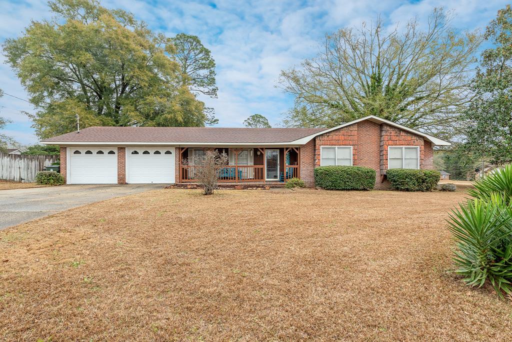 ranch-style house with a porch, a front lawn, and a garage