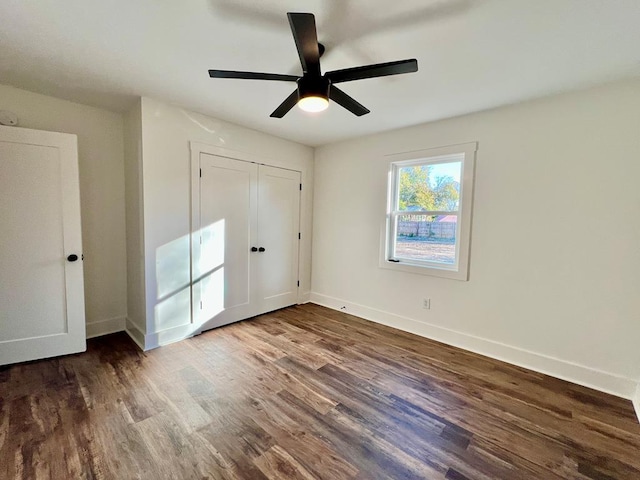 unfurnished bedroom with ceiling fan, a closet, and dark wood-type flooring