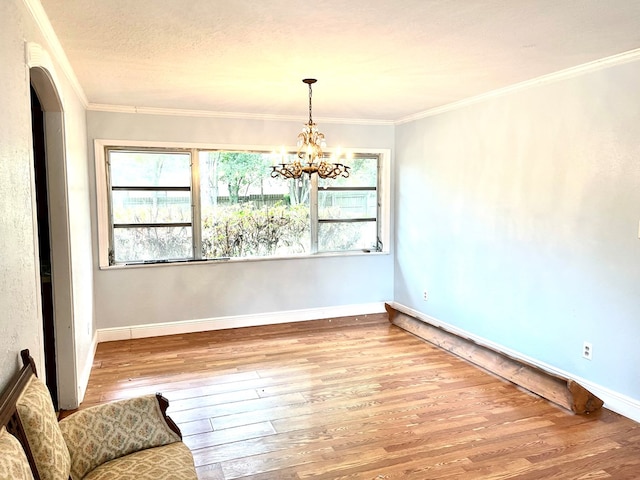 spare room featuring hardwood / wood-style flooring, a textured ceiling, crown molding, and an inviting chandelier