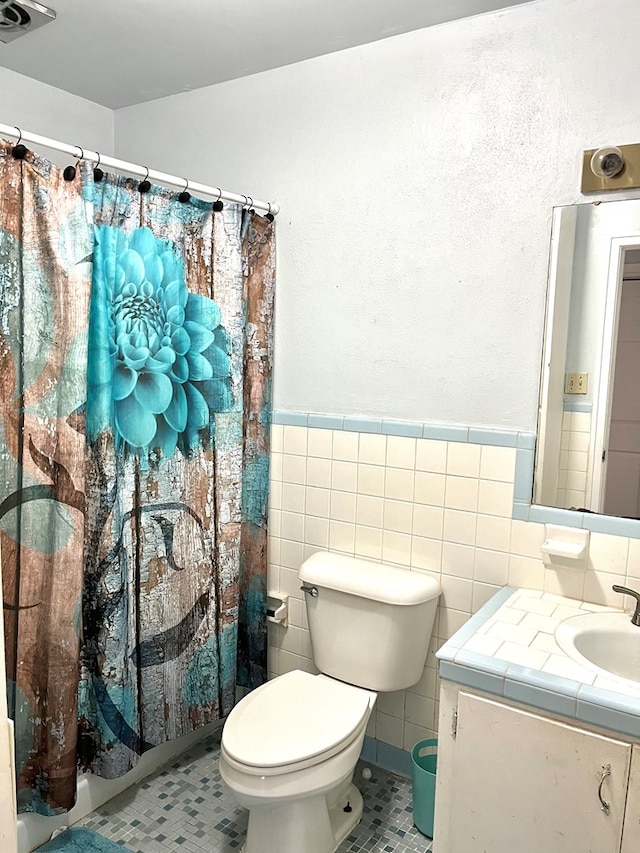 bathroom featuring a shower with curtain, tile patterned floors, toilet, vanity, and tile walls