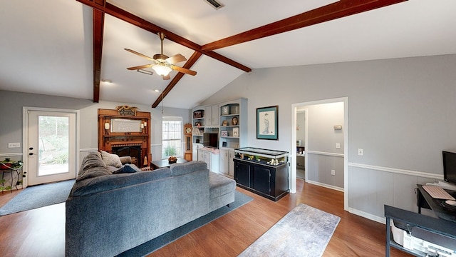 living room featuring wood-type flooring, lofted ceiling with beams, plenty of natural light, and ceiling fan