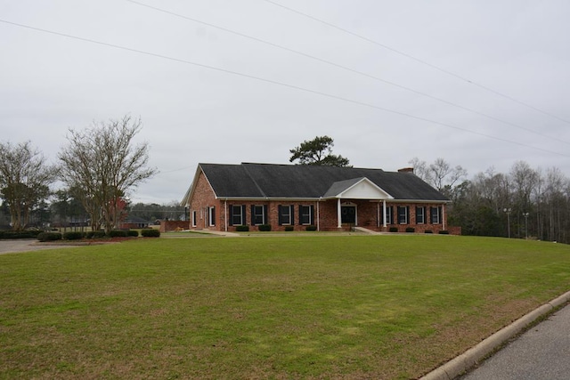 single story home with a chimney, a front lawn, and brick siding
