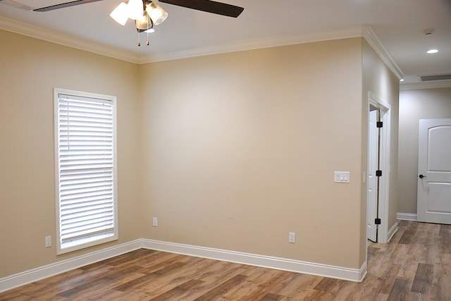 empty room featuring wood finished floors, a ceiling fan, baseboards, visible vents, and crown molding