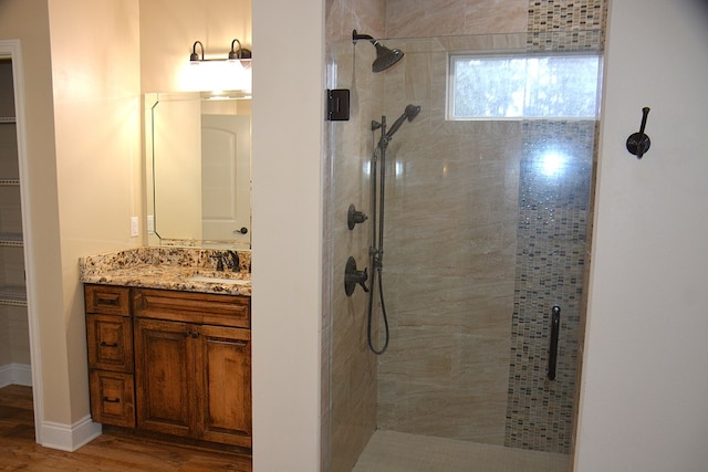 bathroom with a spacious closet, wood finished floors, a shower stall, and vanity