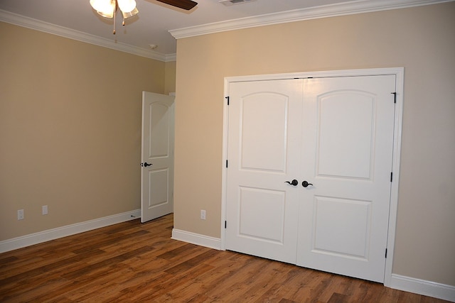 unfurnished bedroom with baseboards, visible vents, ornamental molding, dark wood-style flooring, and a closet