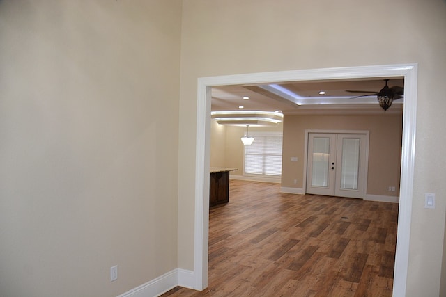 interior space with a tray ceiling, french doors, dark wood-type flooring, and baseboards