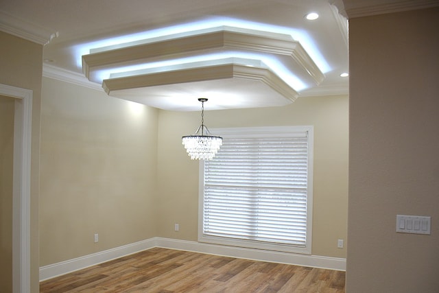 unfurnished room featuring baseboards, a notable chandelier, ornamental molding, and wood finished floors