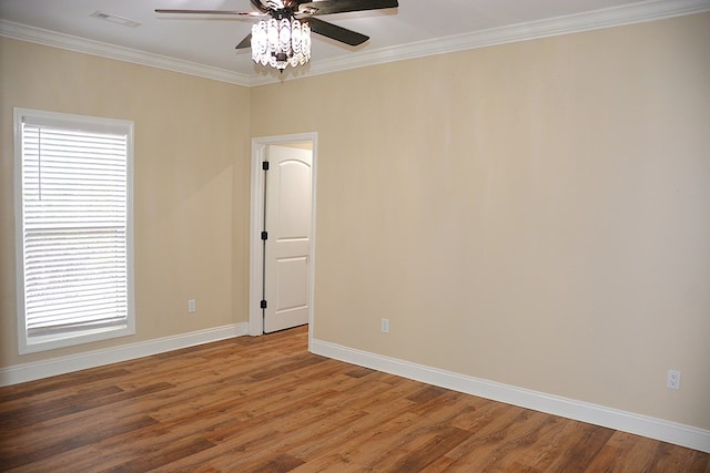 spare room with baseboards, wood finished floors, visible vents, and crown molding