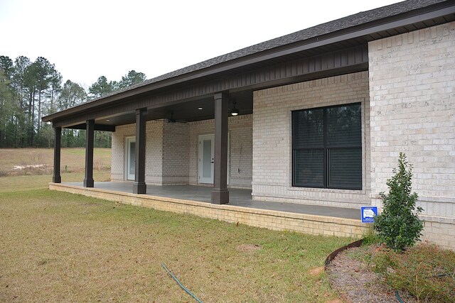 exterior space featuring a patio, a lawn, and brick siding