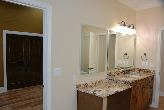 bathroom with crown molding, wood finished floors, and vanity