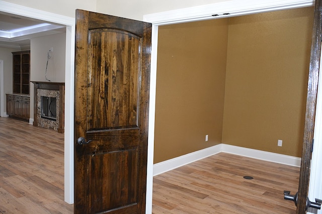 empty room featuring light wood-style flooring, a fireplace, and baseboards