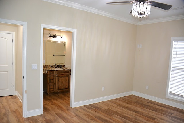 spare room featuring light wood finished floors, ornamental molding, plenty of natural light, and baseboards