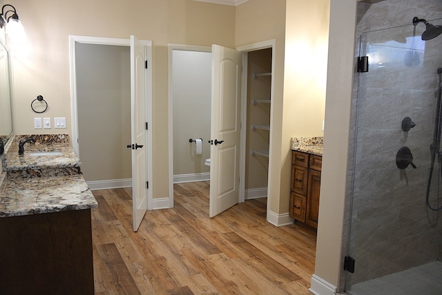 full bath with toilet, a shower stall, vanity, wood finished floors, and baseboards