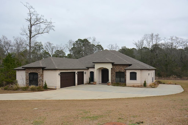 view of front facade with a shingled roof, a front yard, driveway, and an attached garage