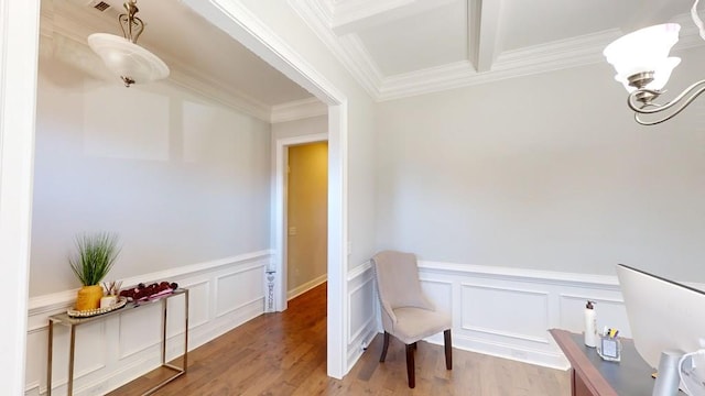 living area with wood-type flooring, ornamental molding, beamed ceiling, and a chandelier