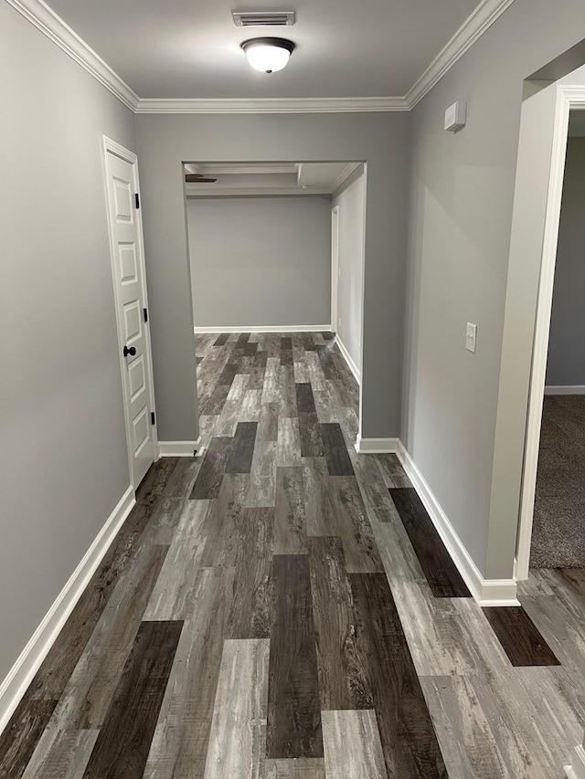 hallway featuring baseboards, crown molding, and wood finished floors
