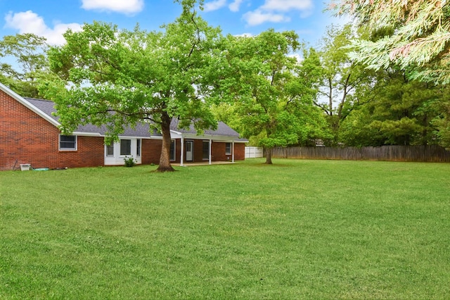 view of yard featuring covered porch and fence