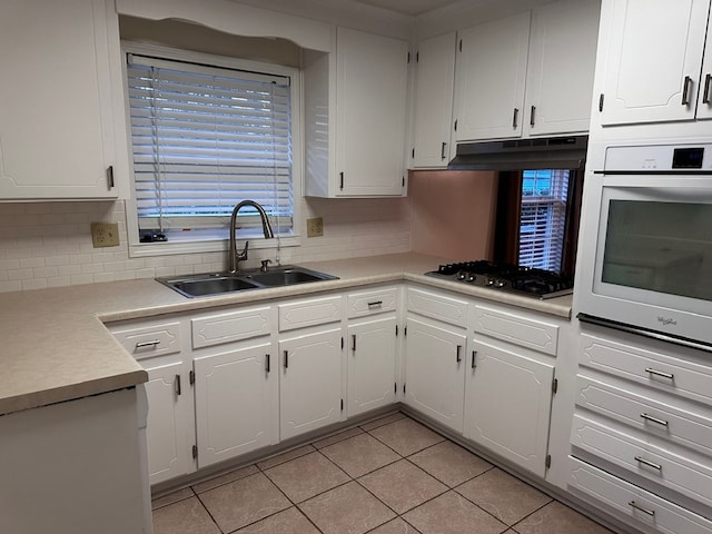 kitchen with white oven, white cabinets, sink, gas stovetop, and light tile patterned floors