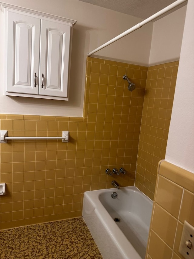 bathroom with tile walls and tiled shower / bath