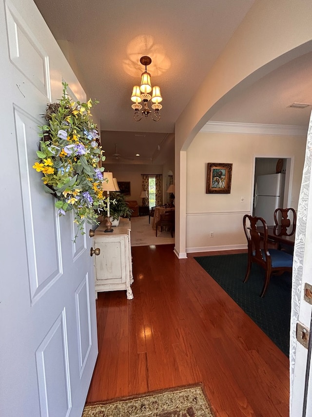 210 Petersburg Ct, Dothan, AL 36301 - entrance foyer featuring dark wood-style flooring, crown molding, arched walkways, baseboards, and an inviting chandelier
