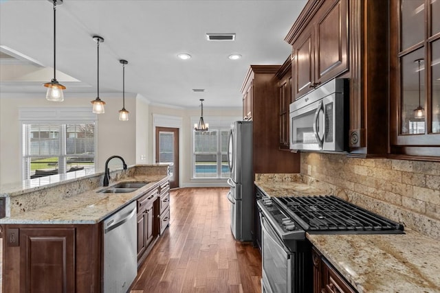 125 Hayley Dr, Enterprise, AL 36330 - kitchen featuring appliances with stainless steel finishes, dark wood-type flooring, a chandelier, tasteful backsplash, and an island with sink