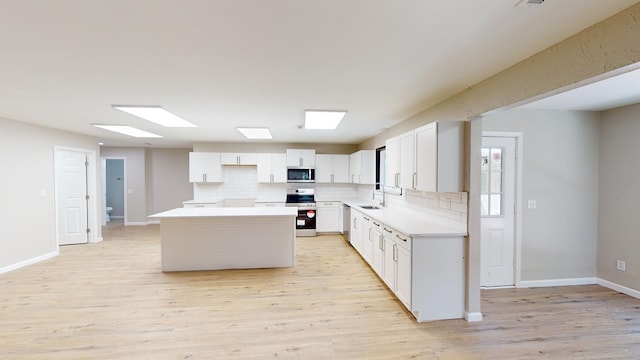 2235 Enterprise Rd, Geneva, AL 36340 - kitchen featuring a center island, light hardwood / wood-style flooring, decorative backsplash, white cabinetry, and stainless steel appliances