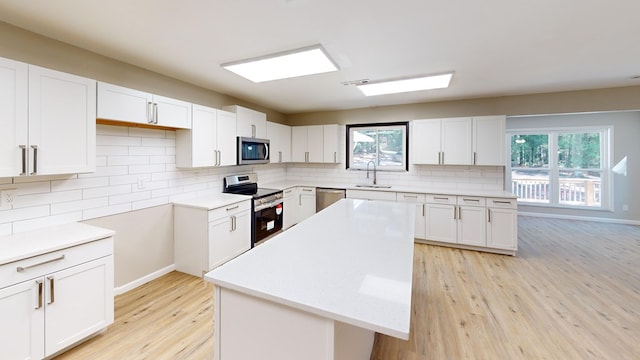 2235 Enterprise Rd, Geneva, AL 36340 - kitchen with sink, light wood-type flooring, appliances with stainless steel finishes, a kitchen island, and white cabinetry