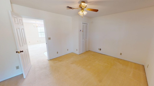 spare room featuring visible vents, light carpet, baseboards, and ceiling fan with notable chandelier