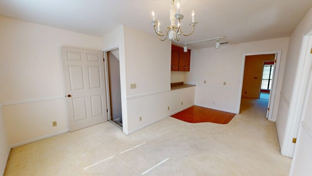 carpeted spare room with baseboards and an inviting chandelier