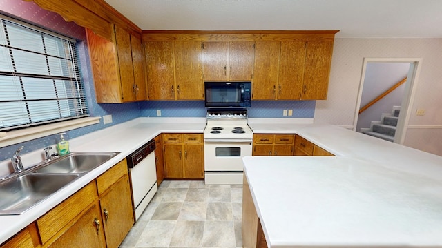 kitchen featuring light countertops, brown cabinets, a peninsula, white appliances, and a sink