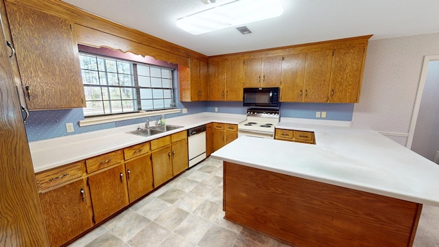 kitchen with brown cabinets, a sink, wallpapered walls, white appliances, and light countertops