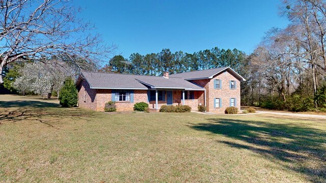 tri-level home featuring brick siding, a chimney, and a front yard