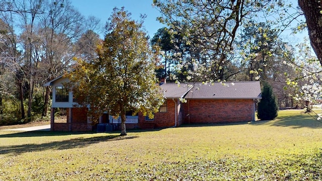 exterior space featuring brick siding, a chimney, and a yard